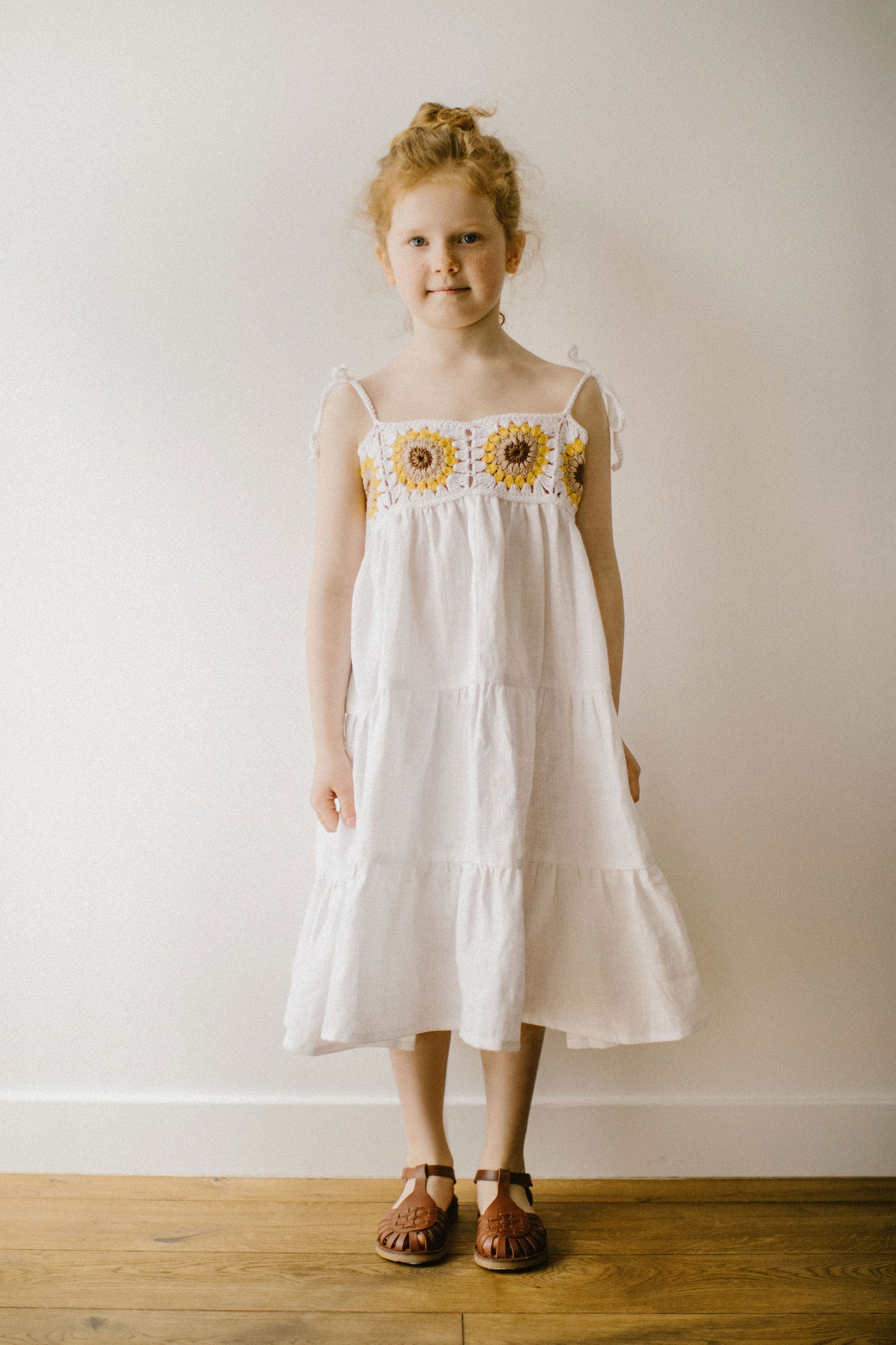 Beautiful girl's white linen dress with crochet sunflowers