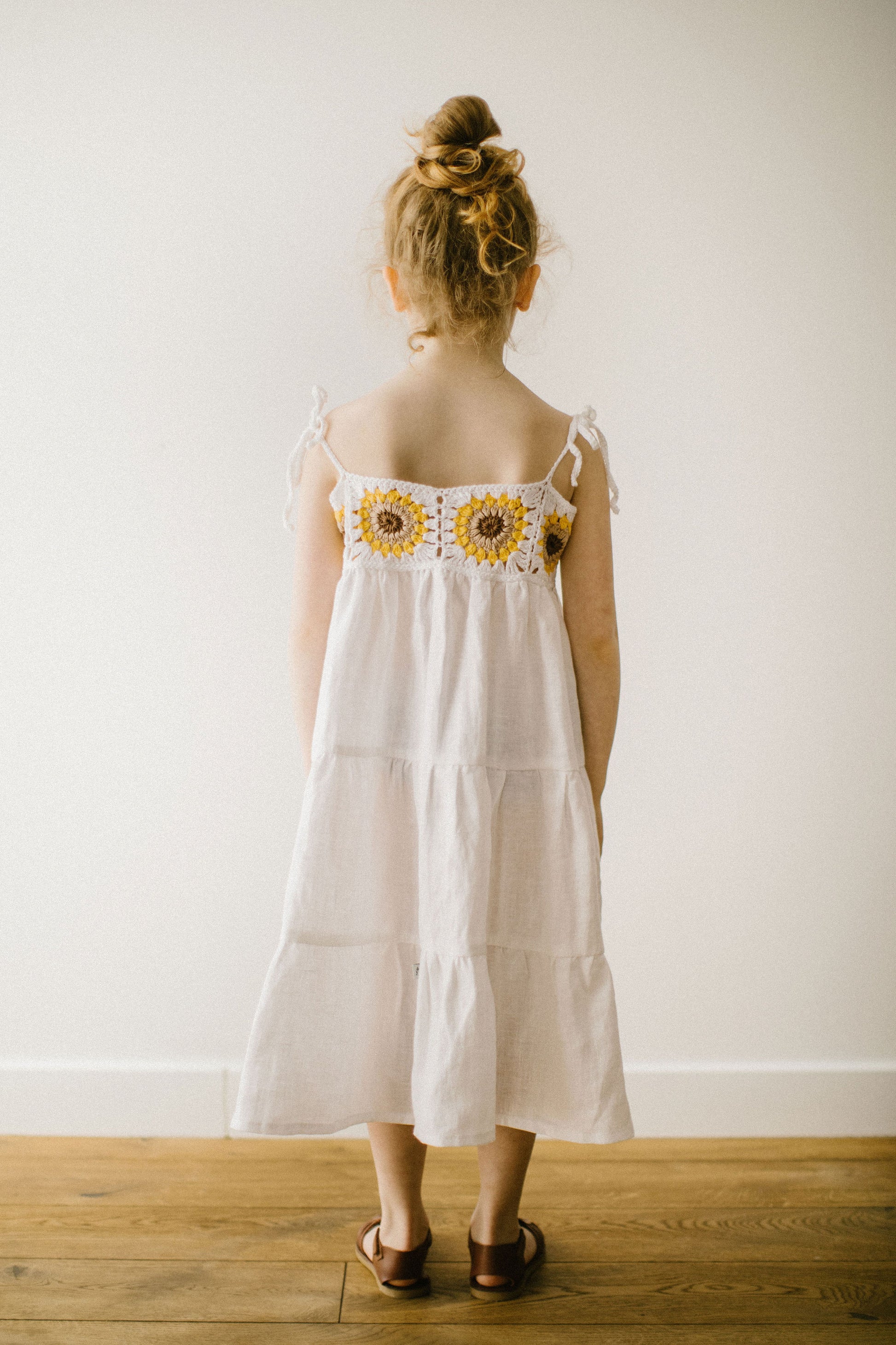 Beautiful girl's white linen dress with crochet sunflowers